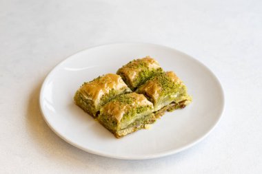 Beyaz arka planda fıstıklı baklava tatlısı. Türk tatlısı konsepti. Bir tabak fıstıklı baklava. Şerbet tatlı Akdeniz fırını. Kapat. Seçici odaklanma. Yatay görüş. Yerel adı fistikli baklava