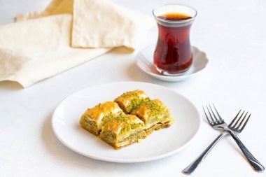Beyaz arka planda fıstıklı baklava tatlısı. Türk tatlısı konsepti. Bir tabak fıstıklı baklava. Şerbet tatlı Akdeniz fırını. Kapat. Seçici odaklanma. Yatay görüş. Yerel adı fistikli baklava