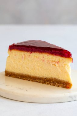 Beyaz arka planda cheesecake. Yunan tatlı tatlı konsepti. Bir tabak dilimlenmiş peynirli kek. Ahududu jöleli cheesecake. Akdeniz pastanesi. Kapat. Seçici odaklanma. Dikey görünüm.