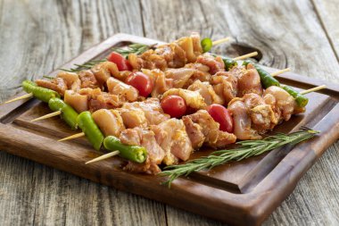 Ahşap arka planda tavuk şişleri. Domates sosunda marine edilmiş çiğ tavuk şişleri. Yatay görünüm