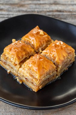 Ahşap zemin üzerinde ceviz baklava. Türk usulü ceviz baklavası sunumu ve servisi. Dikey görünüm. Kapat.