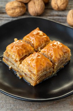 Ahşap zemin üzerinde ceviz baklava. Türk usulü ceviz baklavası sunumu ve servisi. Dikey görünüm. Kapat.