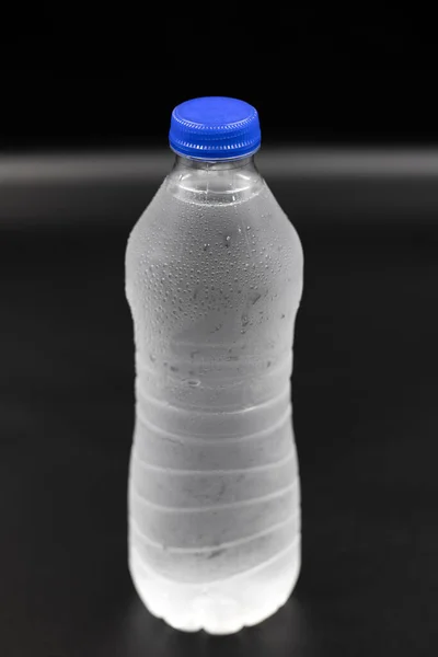 黒を背景に水で満たされたペットボトル 接近中だ 垂直表示 — ストック写真