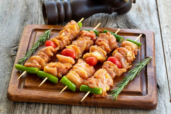 Ahşap arka planda tavuk şişleri. Domates sosunda marine edilmiş çiğ tavuk şişleri. Yatay görünüm