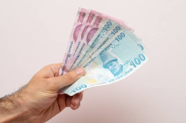 Beyaz duvarın önünde Türk lirası tutan adam