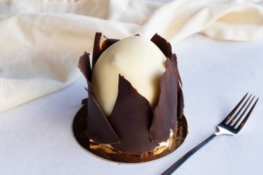 Beyaz arka planda muzlu ve profiterollü kek. Dışında çikolata olan küçük bir kutlama tatlısı.