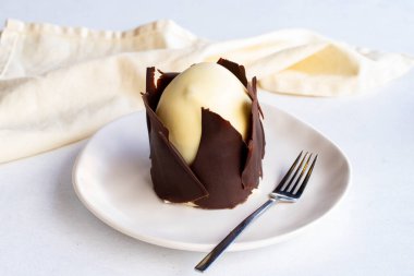 Beyaz arka planda muzlu ve profiterollü kek. Dışında çikolata olan küçük bir kutlama tatlısı.