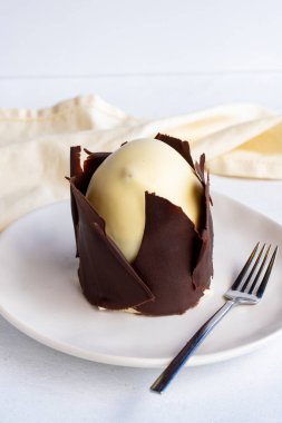 Beyaz arka planda muzlu ve profiterollü kek. Dışında çikolata olan küçük bir kutlama tatlısı.