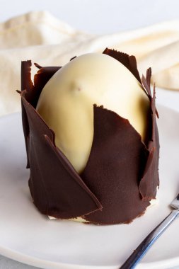 Beyaz arka planda muzlu ve profiterollü kek. Dışında çikolata olan küçük bir kutlama tatlısı.