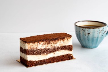 Beyaz arka planda tiramisu keki. Bir fincan kahveyle birlikte.