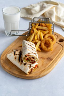 Beyaz arka planda tavuk dürümü. Patates kızartması ve soğan halkalarıyla.