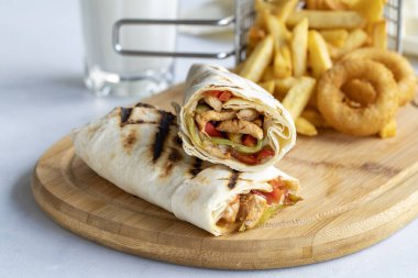 Beyaz arka planda tavuk dürümü. Patates kızartması ve soğan halkalarıyla.