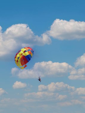 Genç çift mavi gökyüzünde renkli bir paraşütle uçuyor. parasailing