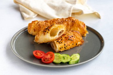 Beyaz arka planda et çorbası. Fırında yeni pişmiş börekler. Zeytin, domates ve salatalıklı.