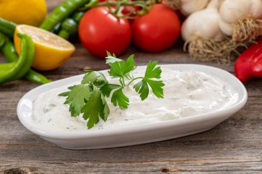 Ahşap bir arka planda Haydari. Haydari, belli otlar ve baharatlardan yapılan bir yoğurt türüdür. Türk mutfağı. Yaklaş, seçici odaklanma
