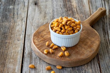 Kızarmış mısır çerezi. Ahşap arka planda soslu mısır çerezi. Toplu mısır ve fındık taneleri. Seramik tabakta kavrulmuş mısır fıstığı.