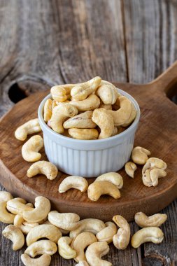 Kavrulmuş kaju fıstığı. Ahşap arka planda kaju fıstığı. Toplu kaju. Seramik tabakta kaju.