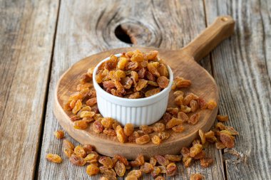 Kuru üzüm. Ahşap zeminde kuru kuru üzümlü fındık. Toplu kuru üzüm taneleri. Seramik tabakta kuru üzüm