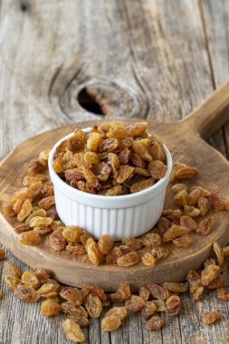 Kuru üzüm. Ahşap zeminde kuru kuru üzümlü fındık. Toplu kuru üzüm taneleri. Seramik tabakta kuru üzüm