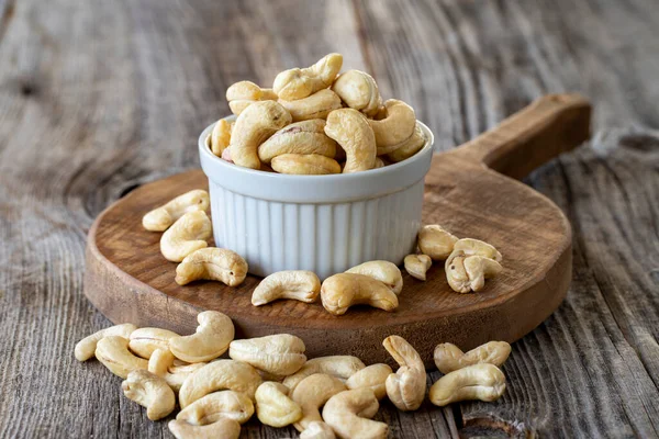 Kavrulmuş kaju fıstığı. Ahşap arka planda kaju fıstığı. Toplu kaju. Seramik tabakta kaju.