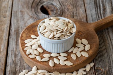 Kabak çekirdeği kabuğu. Ahşap arka planda kabak tohumları. Topak kabak tohumları. Seramik tabakta kabak çekirdeği