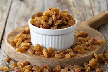 Kuru üzüm. Ahşap zeminde kuru kuru üzümlü fındık. Toplu kuru üzüm taneleri. Seramik tabakta kuru üzüm