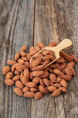 Ahşap arka planda badem fıstığı. Organik ve taze fındık. Badem yığını üzerinde tahta kaşık. Kapat.