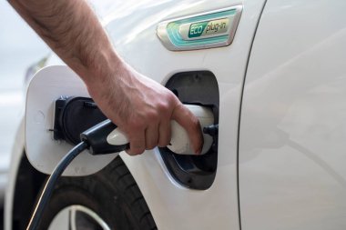 Elektrikli araba şarjı için güç kaynağı. Elektrikli araba şarj istasyonu. Şarj olan bir elektrikli arabaya takılan güç kaynağını kapatın. araba eklentisi hibrit.