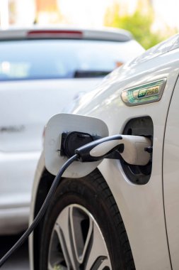 Elektrikli araba şarjı için güç kaynağı. Elektrikli araba şarj istasyonu. Şarj olan bir elektrikli arabaya takılan güç kaynağını kapatın. araba eklentisi hibrit.