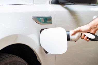 Elektrikli araba şarjı için güç kaynağı. Elektrikli araba şarj istasyonu. Şarj olan bir elektrikli arabaya takılan güç kaynağını kapatın. araba eklentisi hibrit.