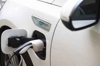 Elektrikli araba şarjı için güç kaynağı. Elektrikli araba şarj istasyonu. Şarj olan bir elektrikli arabaya takılan güç kaynağını kapatın. araba eklentisi hibrit.