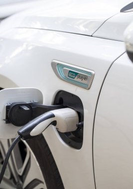 Elektrikli araba şarjı için güç kaynağı. Elektrikli araba şarj istasyonu. Şarj olan bir elektrikli arabaya takılan güç kaynağını kapatın. araba eklentisi hibrit.