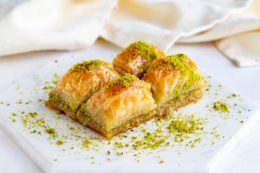 Beyaz ahşap arka planda fıstıklı baklava. Mermer zeminde Baklava