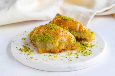 Beyaz ahşap arka planda fıstıklı sobiyet baklavası. Mermer zeminde baklava. Kapat.