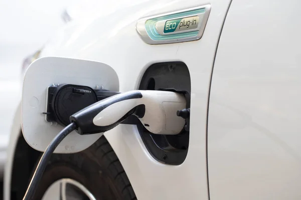 Elektrikli araba şarjı için güç kaynağı. Elektrikli araba şarj istasyonu. Şarj olan bir elektrikli arabaya takılan güç kaynağını kapatın. araba eklentisi hibrit.