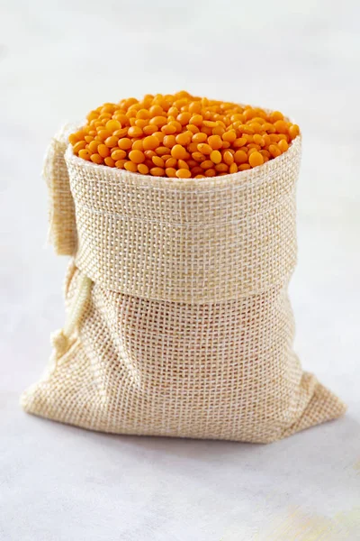 Red Lentils grains are in the sack. Red Lentils grains on white background.