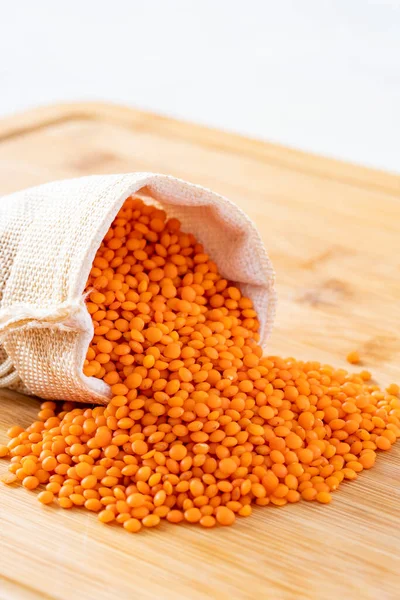 Red Lentils grains are in the sack. Red Lentils grains on wooden background.