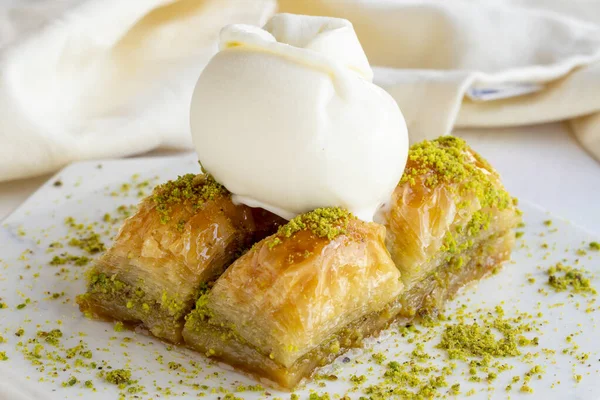 Beyaz ahşap arka planda dondurmalı Pistachio baklava. Mermer zeminde baklava. Dondurma baklavası. Kapat.