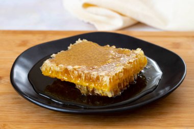 Ahşap arka planda organik bal peteği. Tabakta bal var.