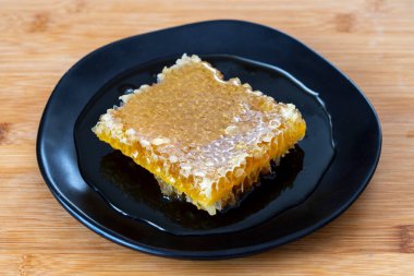 Ahşap arka planda organik bal peteği. Tabakta bal var.