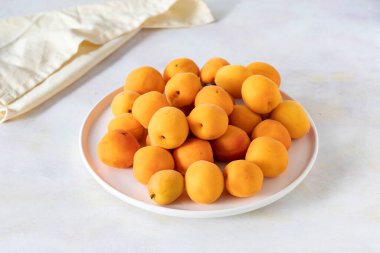 Beyaz seramik tabakta taze kayısılar.