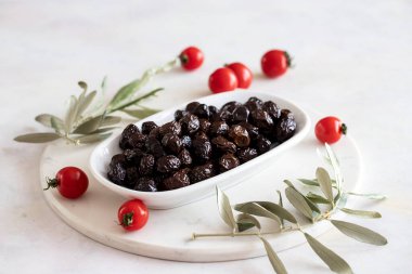 Siyah zeytin. Tabakta organik siyah zeytinler var. Mermer zeminde zeytin