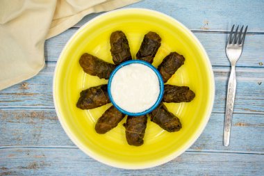 Et yaprağı ambalajı. Geleneksel Akdeniz aroması. Mavi ahşap arka planda yoğurtlu sarılmış yapraklar. yerel adı etli yaprak sarma