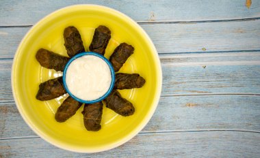 Et yaprağı ambalajı. Geleneksel Akdeniz aroması. Mavi ahşap arka planda yoğurtlu sarılmış yapraklar. yerel adı etli yaprak sarma