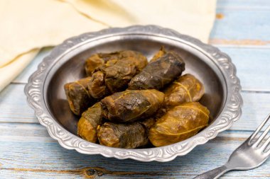 Et yaprağı ambalajı. Geleneksel Akdeniz aroması. Mavi arka planda yoğurtlu sarılmış yapraklar. yerel adı etli yaprak sarma