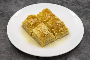 Sütlü Baklava (sutlu nuriye). Fındıklı baklava ve koyu arkaplanda süt..