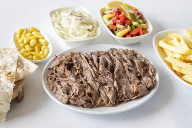 Beyaz arka planda döner kebap. Geleneksel Türk mutfağı çeşnili et donörü. Lavaş ekmeği, patates kızartması, salata ve soğanlı.