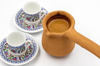 Beyaz arka planda kil çömlekte Türk kahvesi. Geleneksel Türk mutfağı aroması. Kapat.