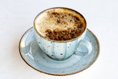 Beyaz arka planda sütlü kahve. Masada süt olan bir fincan kahve. Kapat.