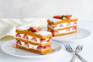 Beyaz arka planda çilekli kek dilimi. Kremalı ve çilekli bir pasta. Kapat.